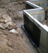 Foundation waterproofing system applied to concrete retaining walls before backfilling